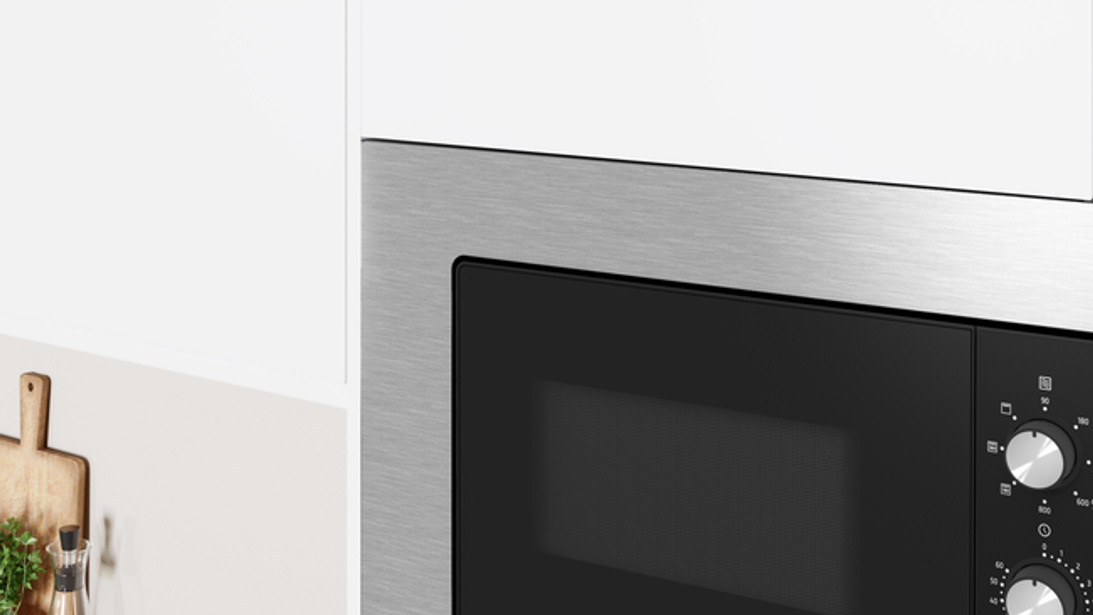 Kuchenka mikrofalowa ze stali nierdzewnej, obramowana białymi szafkami.