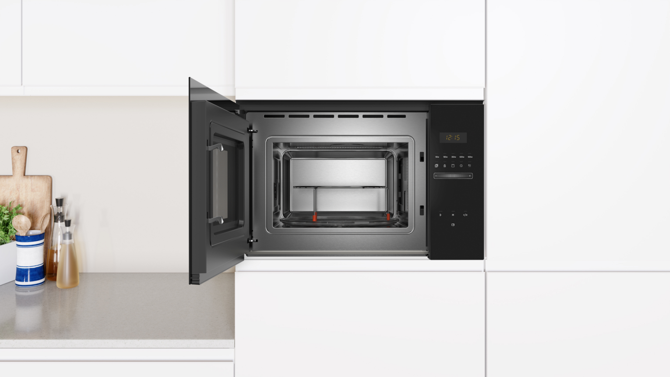 Kuchenka mikrofalowa, otwarta. Widoczne wnętrze, ze szklaną tacą i elementami sterującymi. W białej szafce.