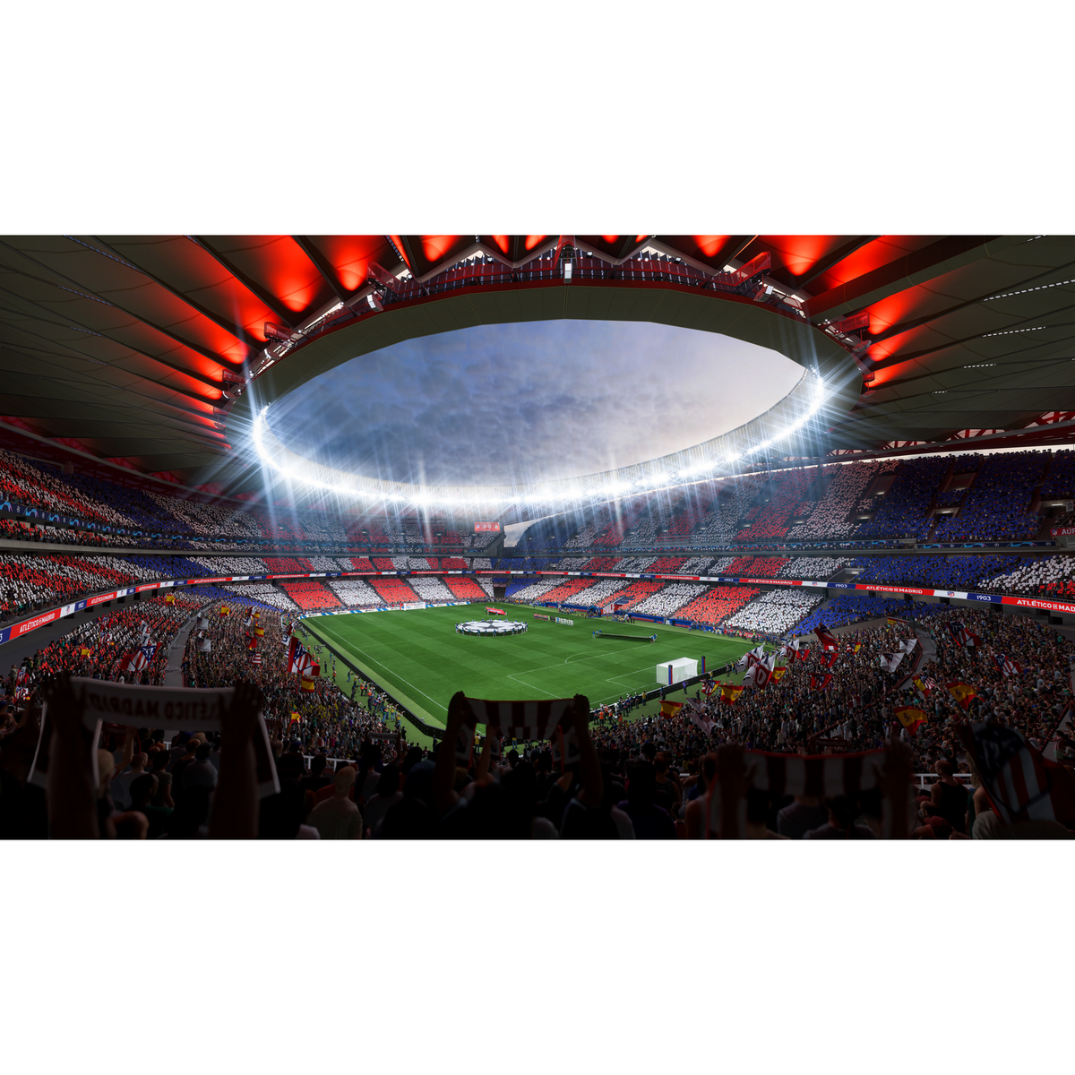 Pełen stadion z czerwonymi, białymi i niebieskimi siedzeniami. Boisko jest zielone, pod jasnym, słonecznym niebem.