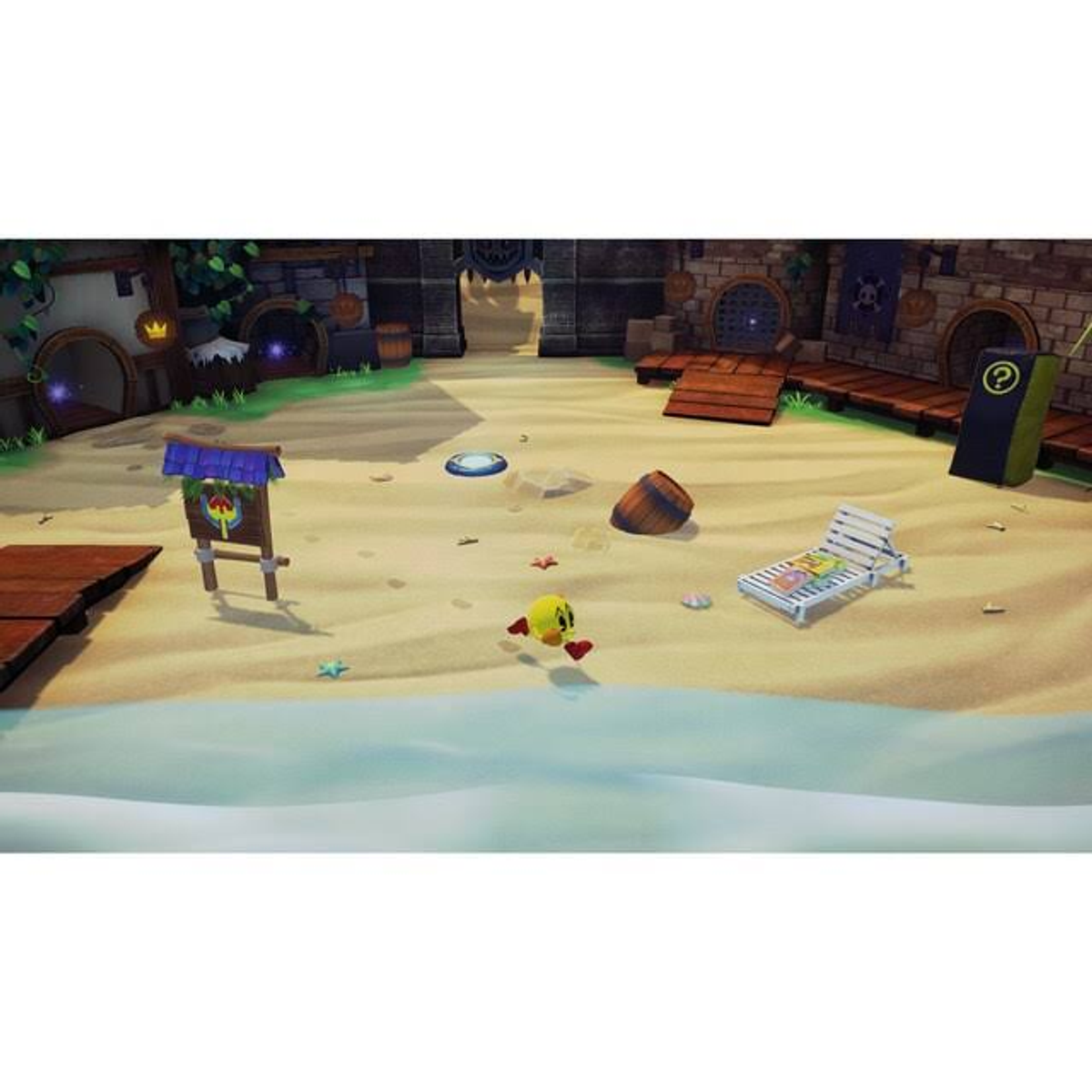 Pac-Man na plaży. Jest blisko wody. W tle leżaki i znak.