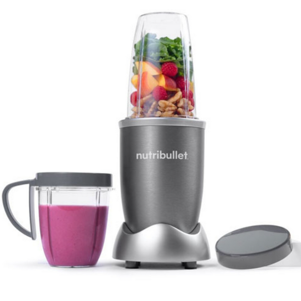 Una licuadora con frutas y nueces, y una taza de batido rosa.