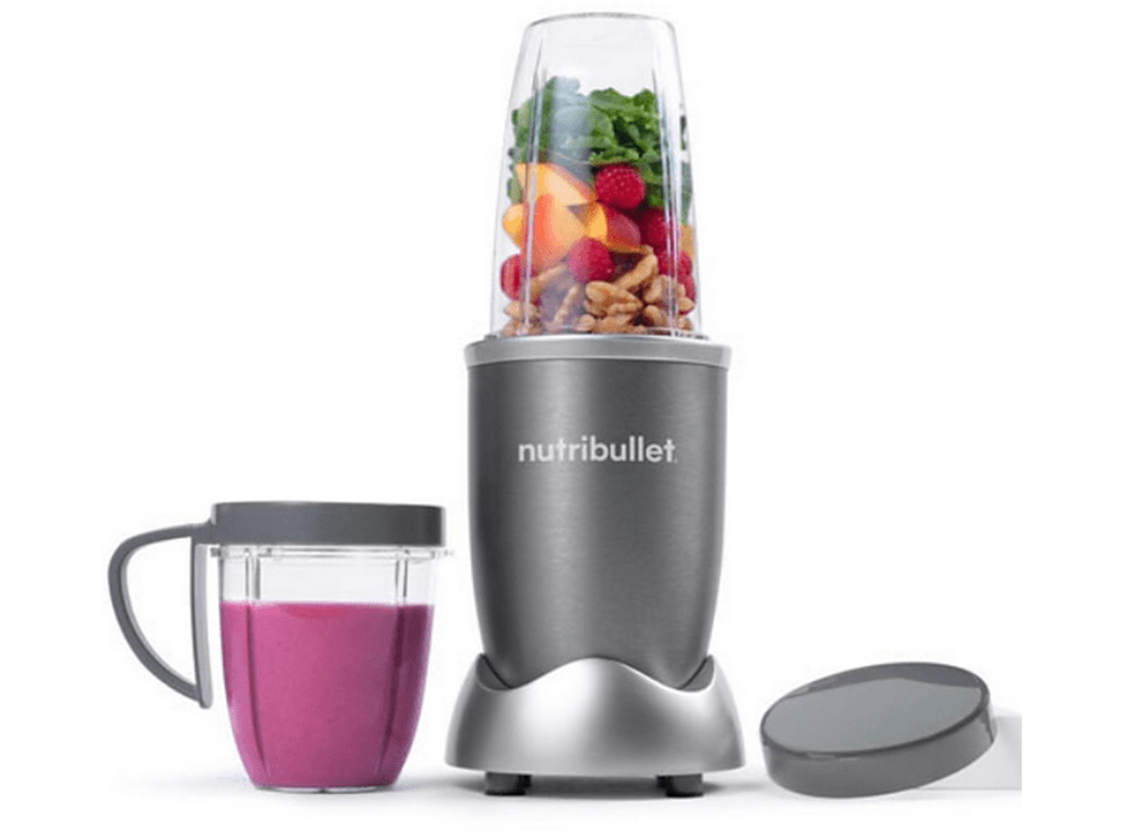 Licuadora NutriBullet con ingredientes, batido rosa en taza, tapa gris a la derecha.