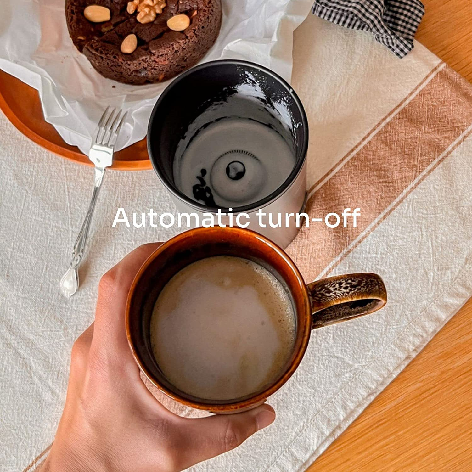 Mano che tiene una tazza di caffè. Macina e torta sullo sfondo.