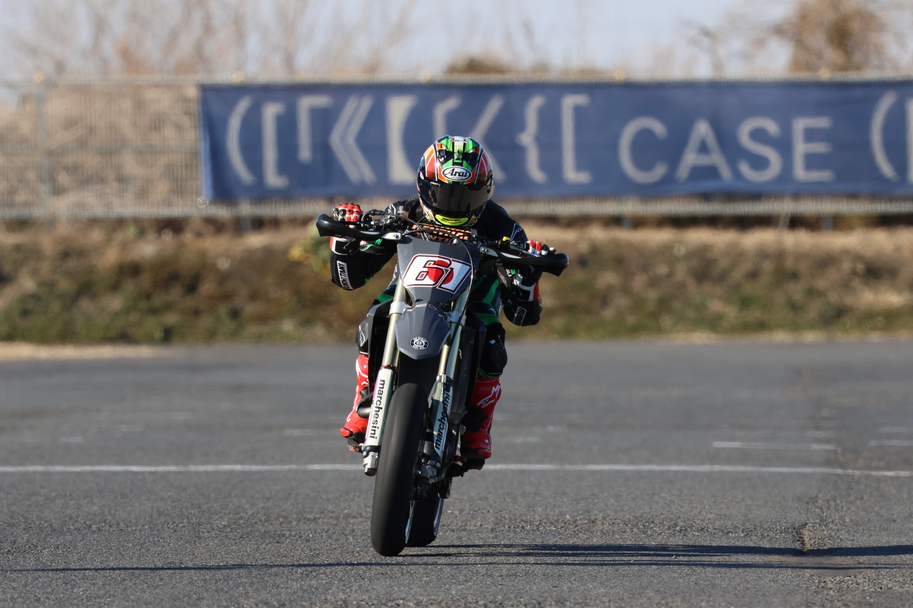 Kierowca motocykla na torze, pochylony w zakręcie, widok z przodu, w dzień.