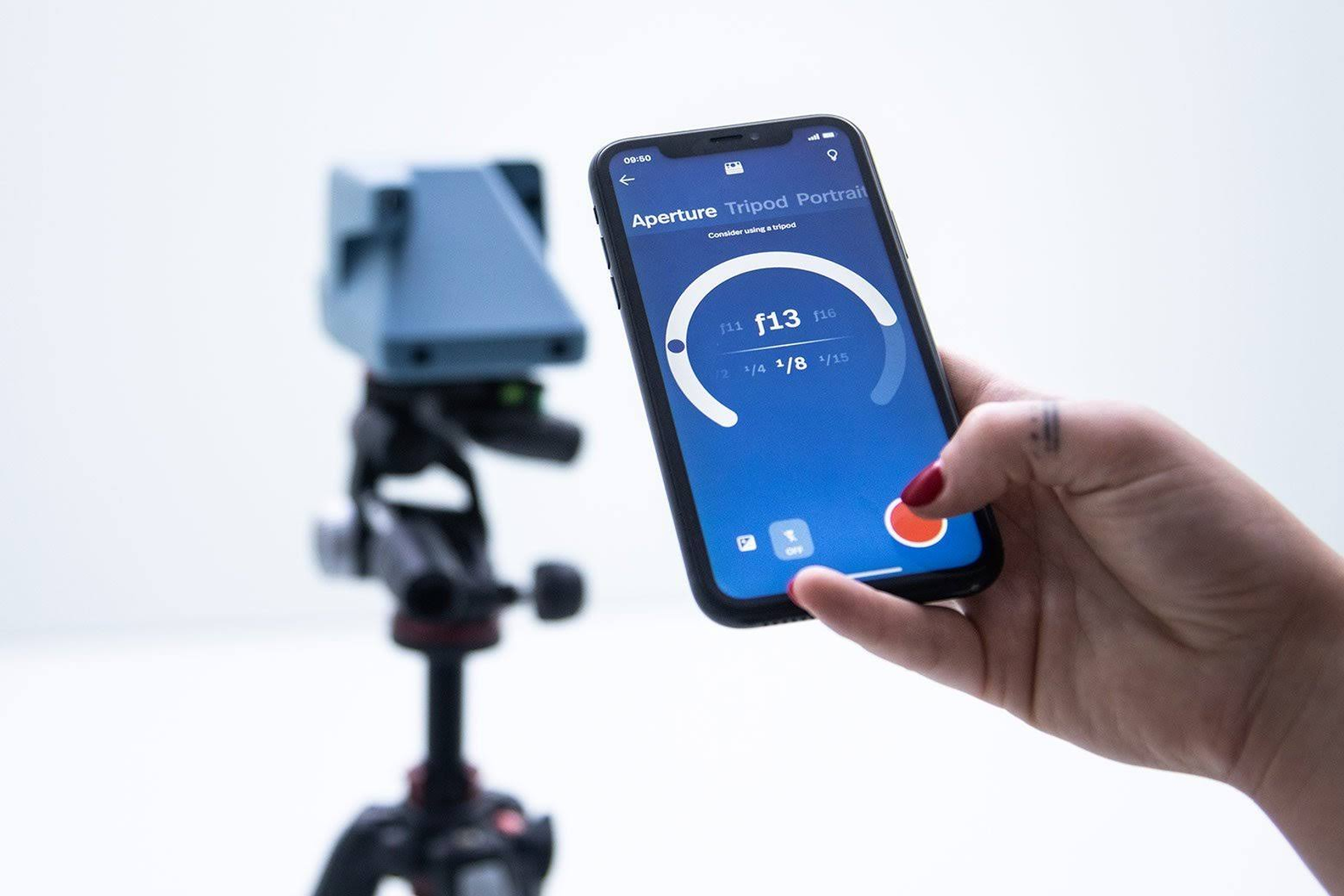 Eine Person, die ein Telefon mit einer Kamera-App mit Einstellungen hält, im Hintergrund ein Stativ.