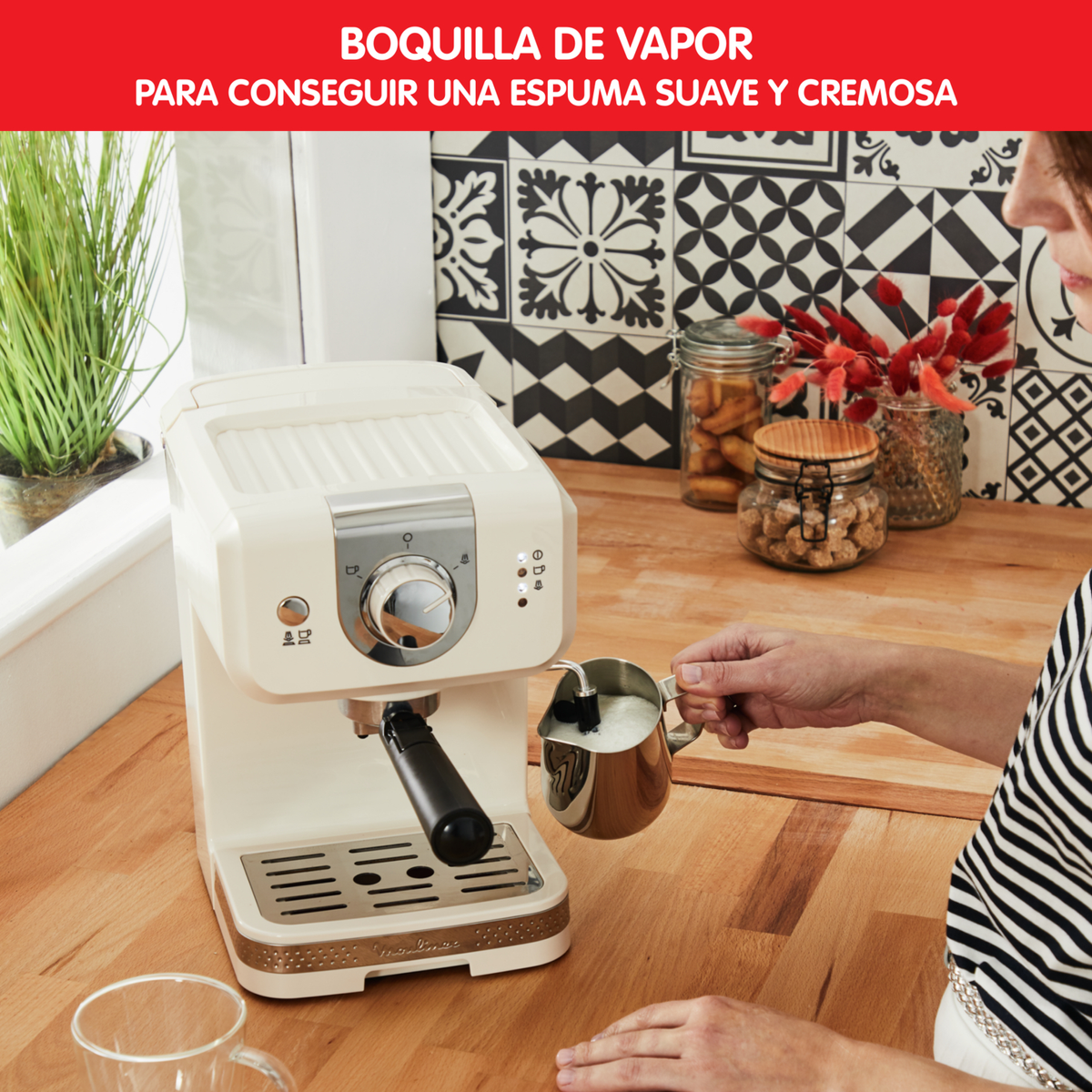 Osoba spienia mleko do metalowego dzbanka za pomocą ekspresu do kawy. Maszyna jest kremowa.