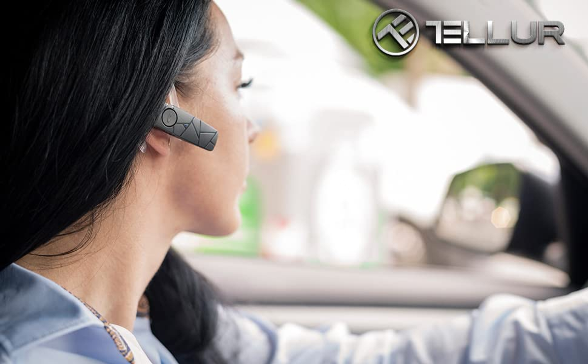 Eine Frau in einem Auto, die ein schwarzes Bluetooth-Headset trägt. Der Markenname Tellur ist sichtbar.