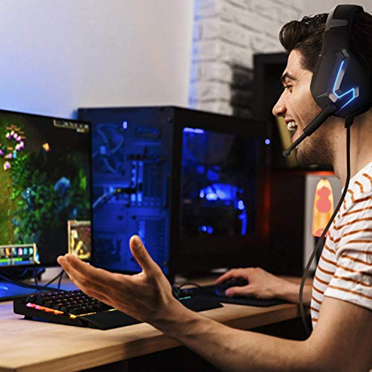 Una persona sta giocando usando cuffie e tastiera. Un computer e un monitor sono sullo sfondo.