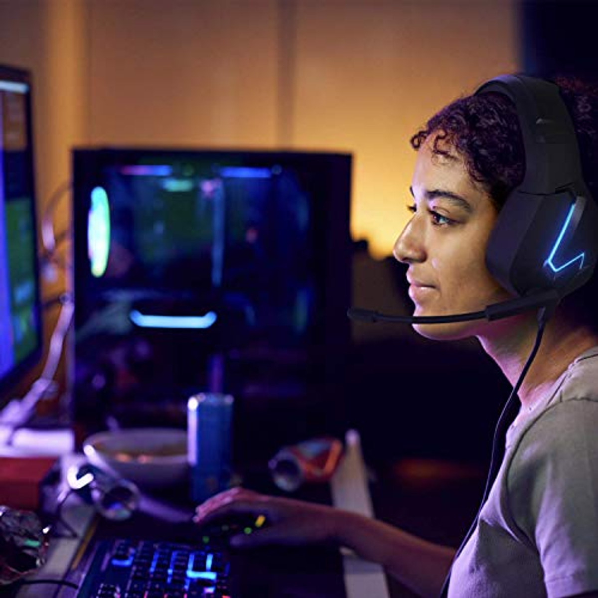 Una donna indossa le cuffie mentre gioca. Sta guardando un monitor e usando un mouse.
