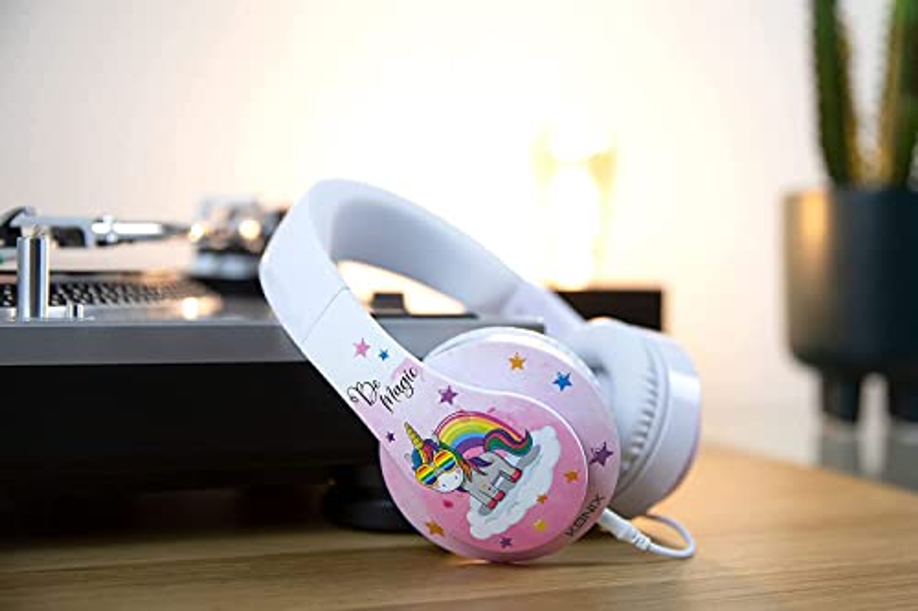 Cuffie rosa con design unicorno. Su un tavolo, con un giradischi e una pianta.