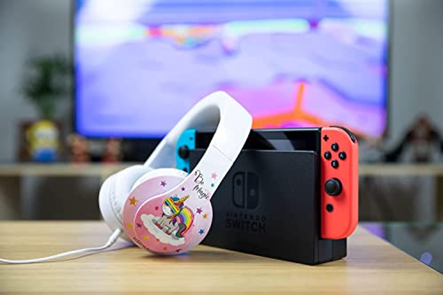 Cuffie bianche con design unicorno, accanto a una console Nintendo Switch. Sfondo sfocato.