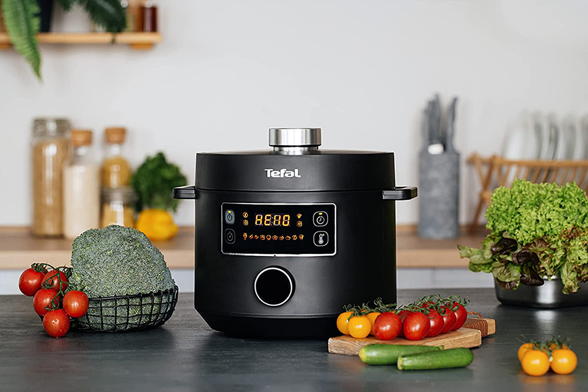 Schwarzer Schnellkochtopf mit Digitalanzeige, Gemüse und Tomaten. Küchenhintergrund.