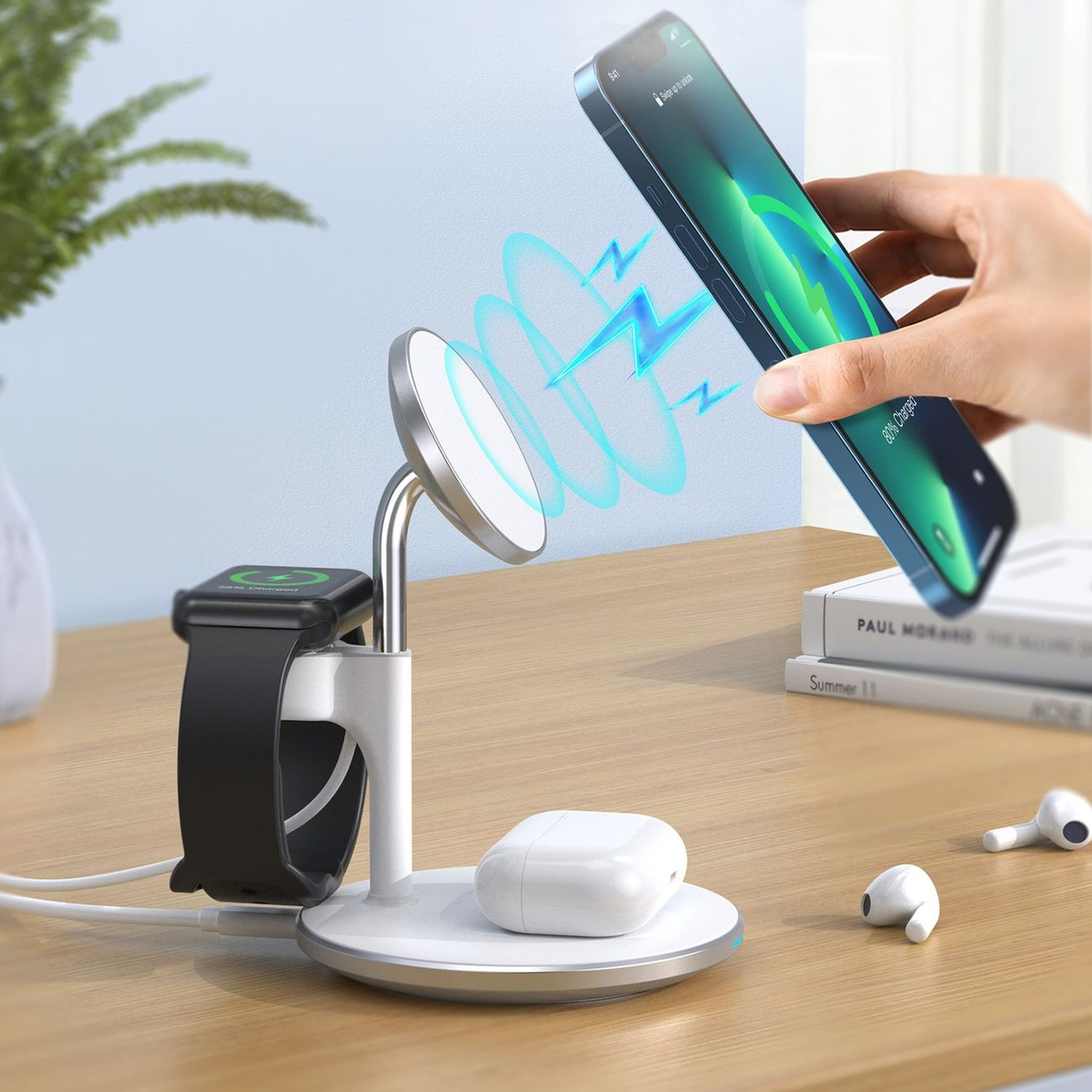 Ladestation mit Telefon, Uhr, AirPods. Hand hält Telefon über das Ladepad. Weiße und graue Farben.