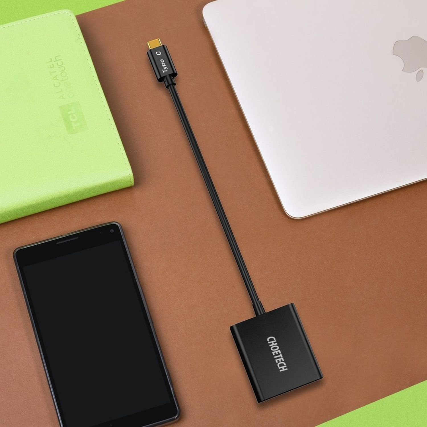 Telefon und Laptop mit schwarzem Adapter. Grüne und braune Oberfläche. Draufsicht.