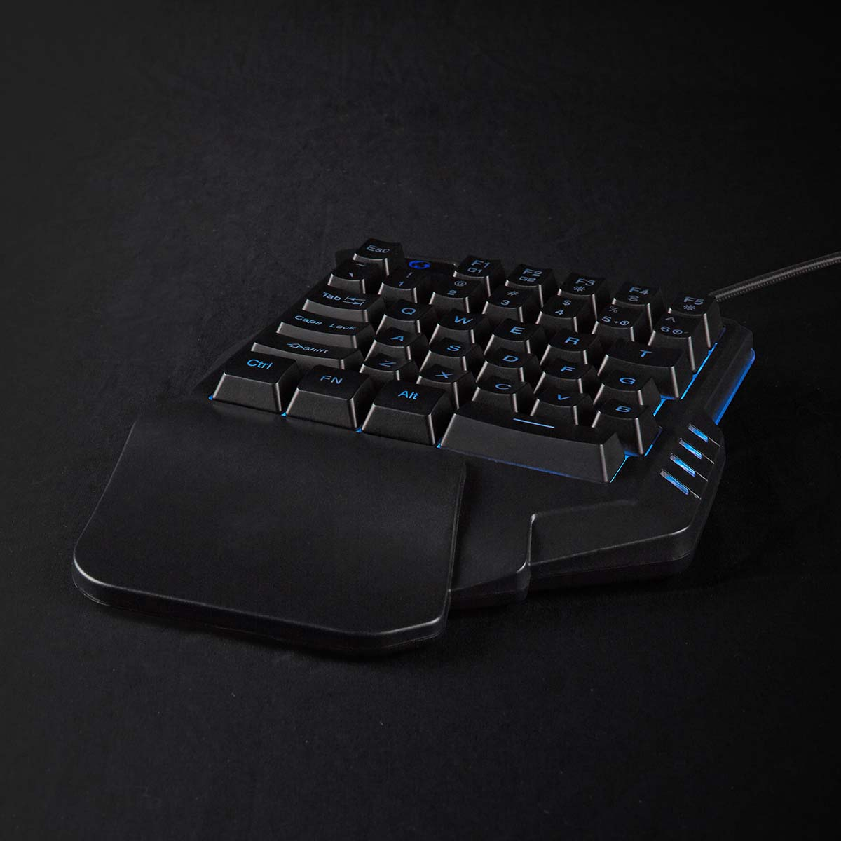 Schwarze ergonomische Tastatur mit blauem Licht und Handballenauflage auf dunkler Oberfläche.