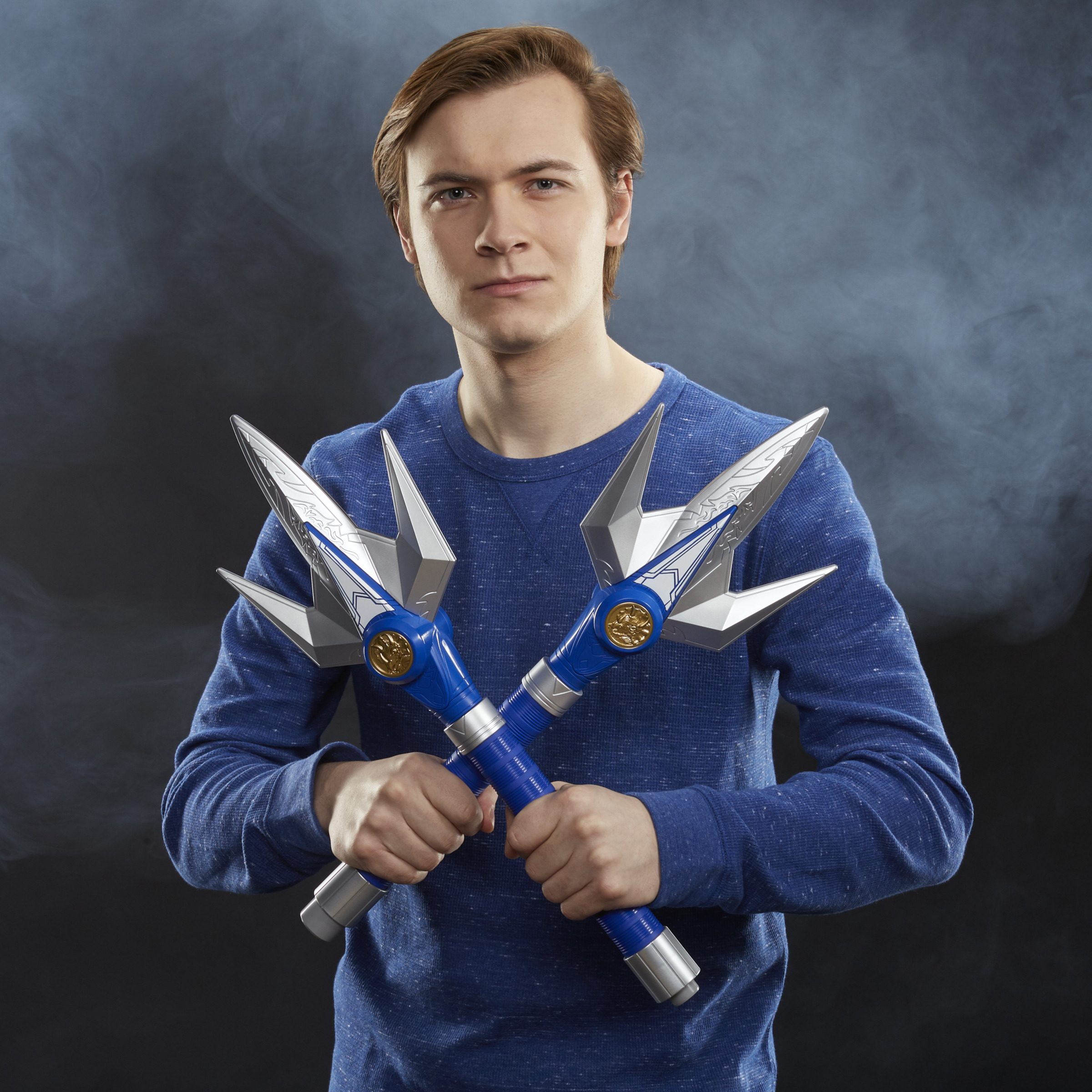 Un uomo con capelli castani tiene due lance blu e argentate incrociate.