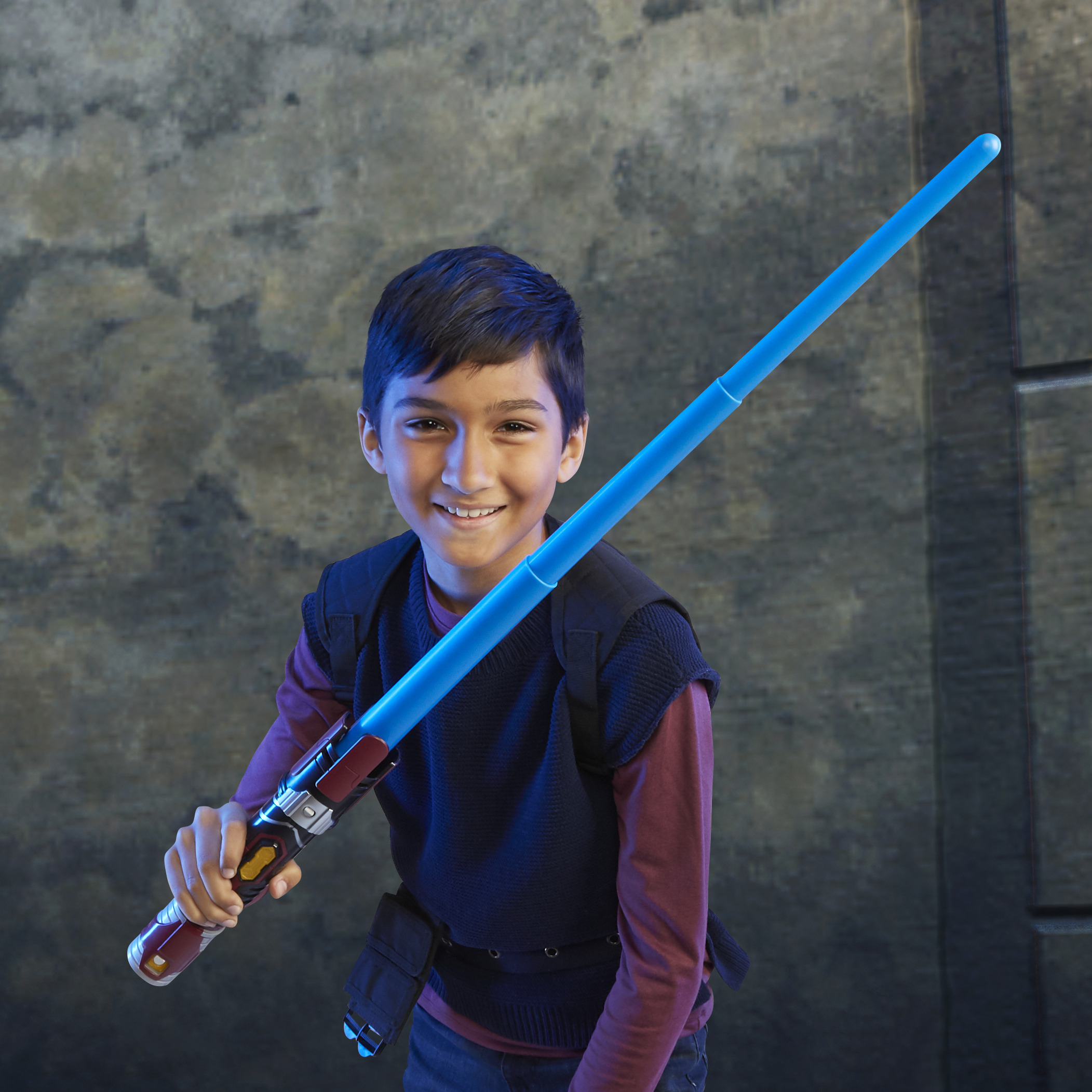 Un niño sosteniendo un sable de luz azul. Él está sonriendo.