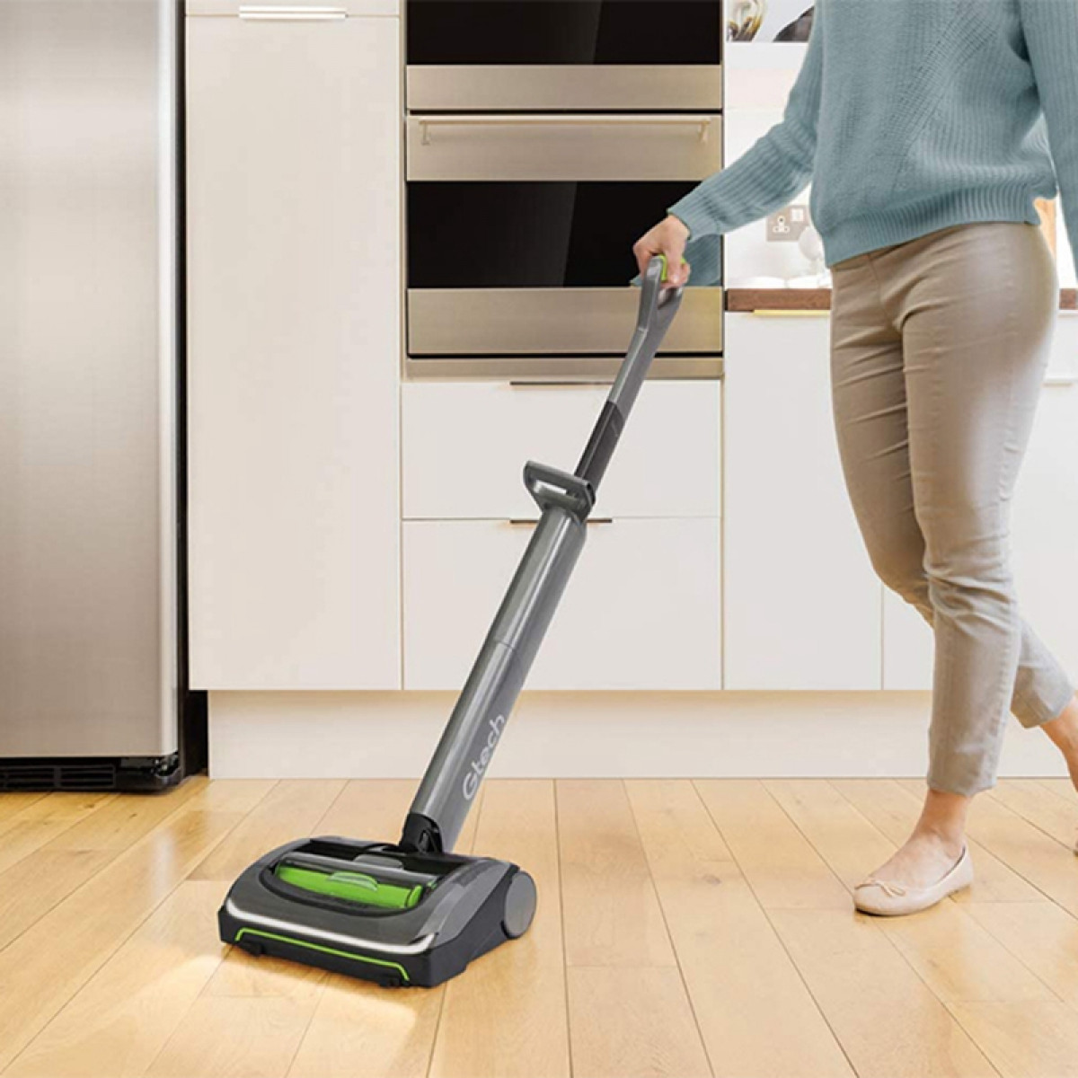 Eine Frau benutzt einen kabellosen Staubsauger auf einem Holzboden.