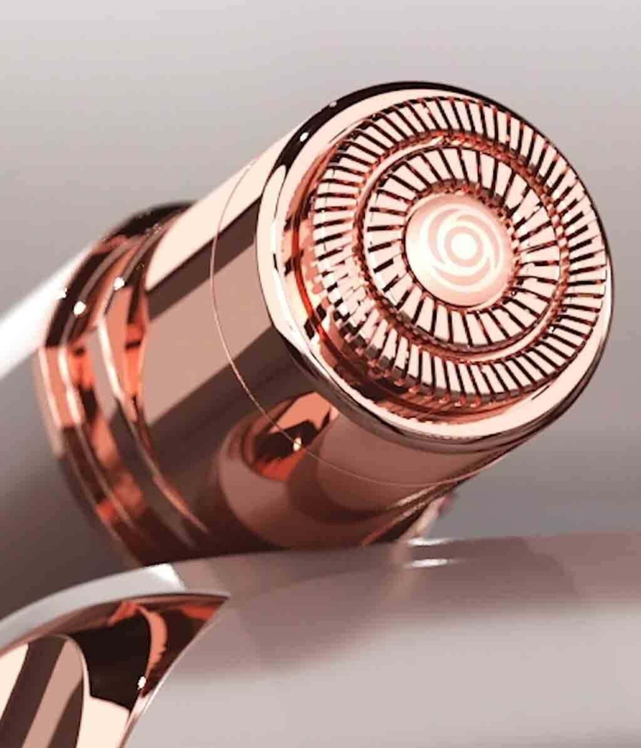 Primo piano di un rasoio viso oro rosa, che mostra la testina di rasatura circolare.