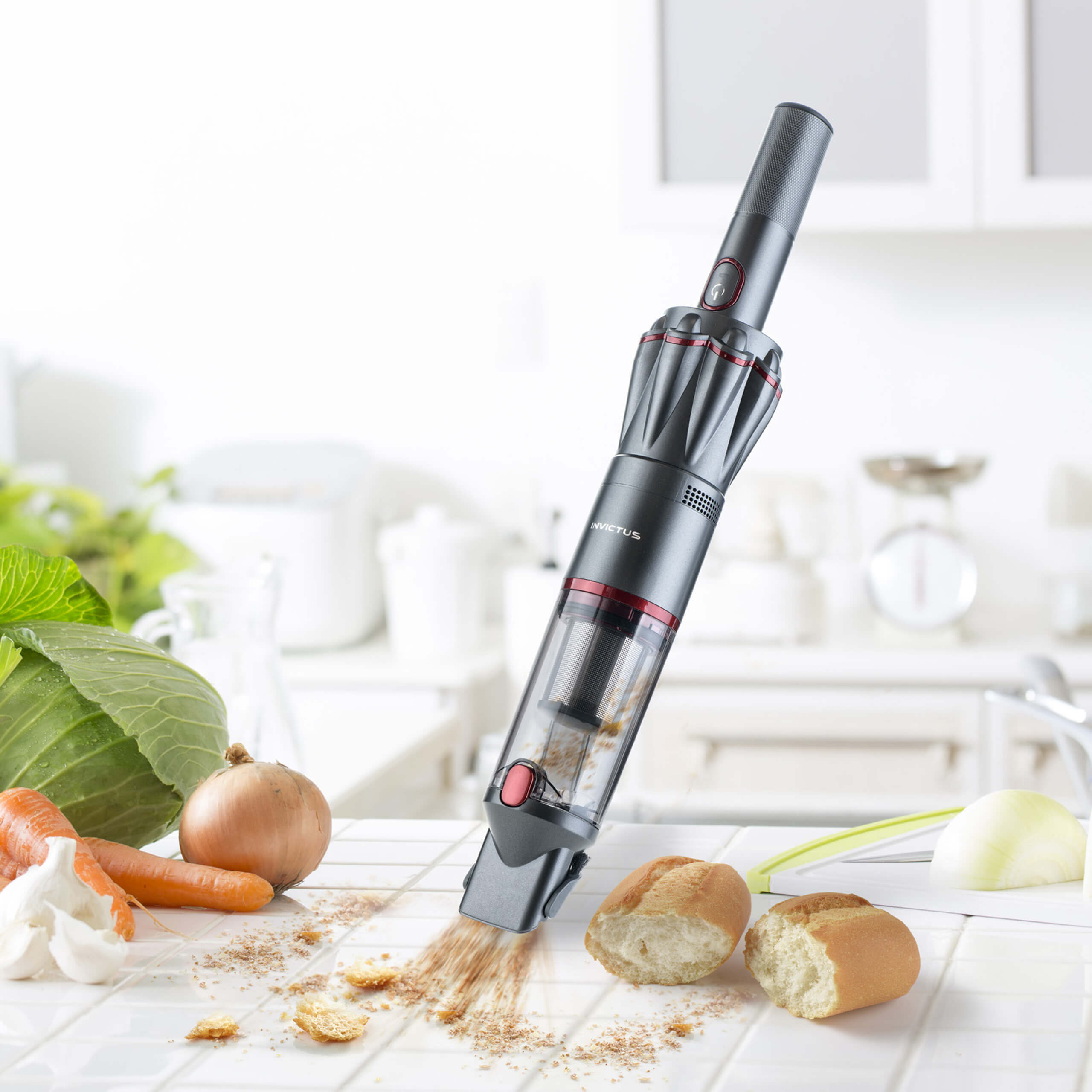 Ein Staubsauger reinigt Krümel auf einer weißen Küchentheke. Gemüse ist sichtbar.