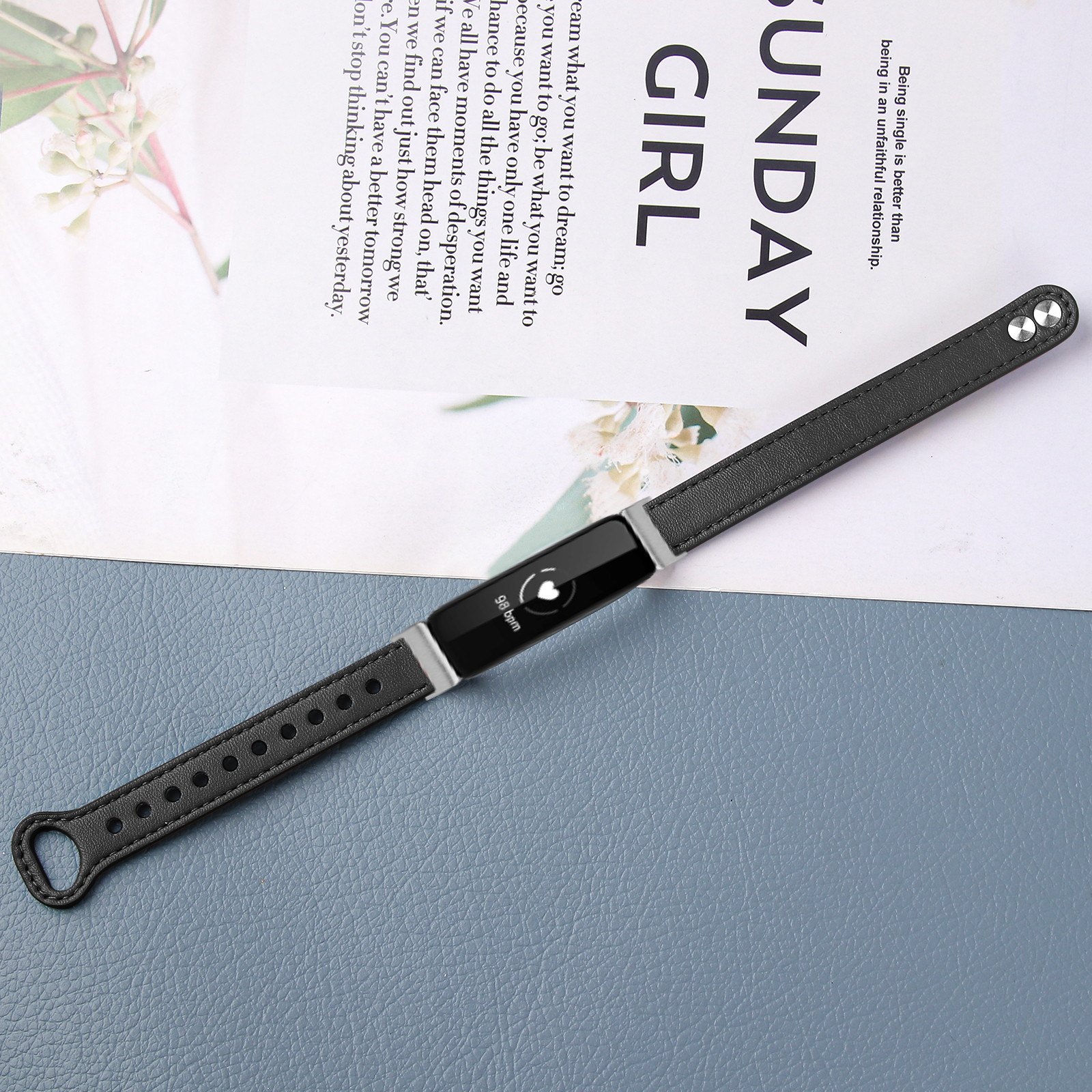 Schwarzer Fitness-Tracker auf einem Magazin mit Text. Der Tracker hat einen Bildschirm und ein schwarzes Armband.
