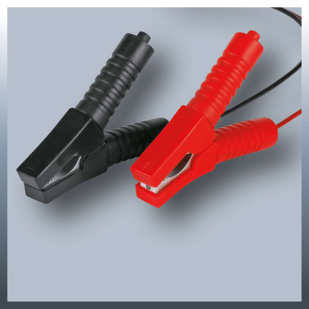 Schwarze und rote Autobatterieklemmen. Graue Oberfläche mit quadratischem Schatten.