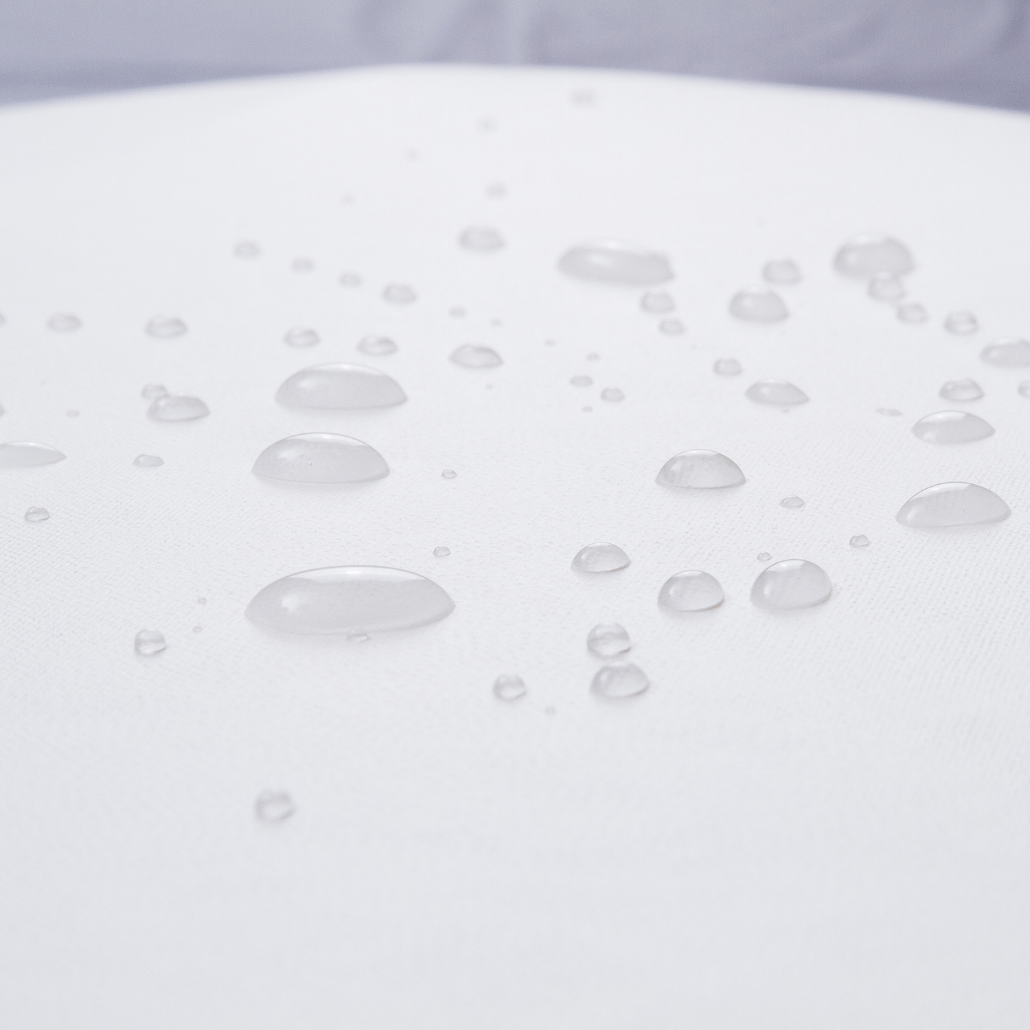 Primer plano de gotas de agua sobre tela blanca. Las gotas son claras y reflejan la luz.