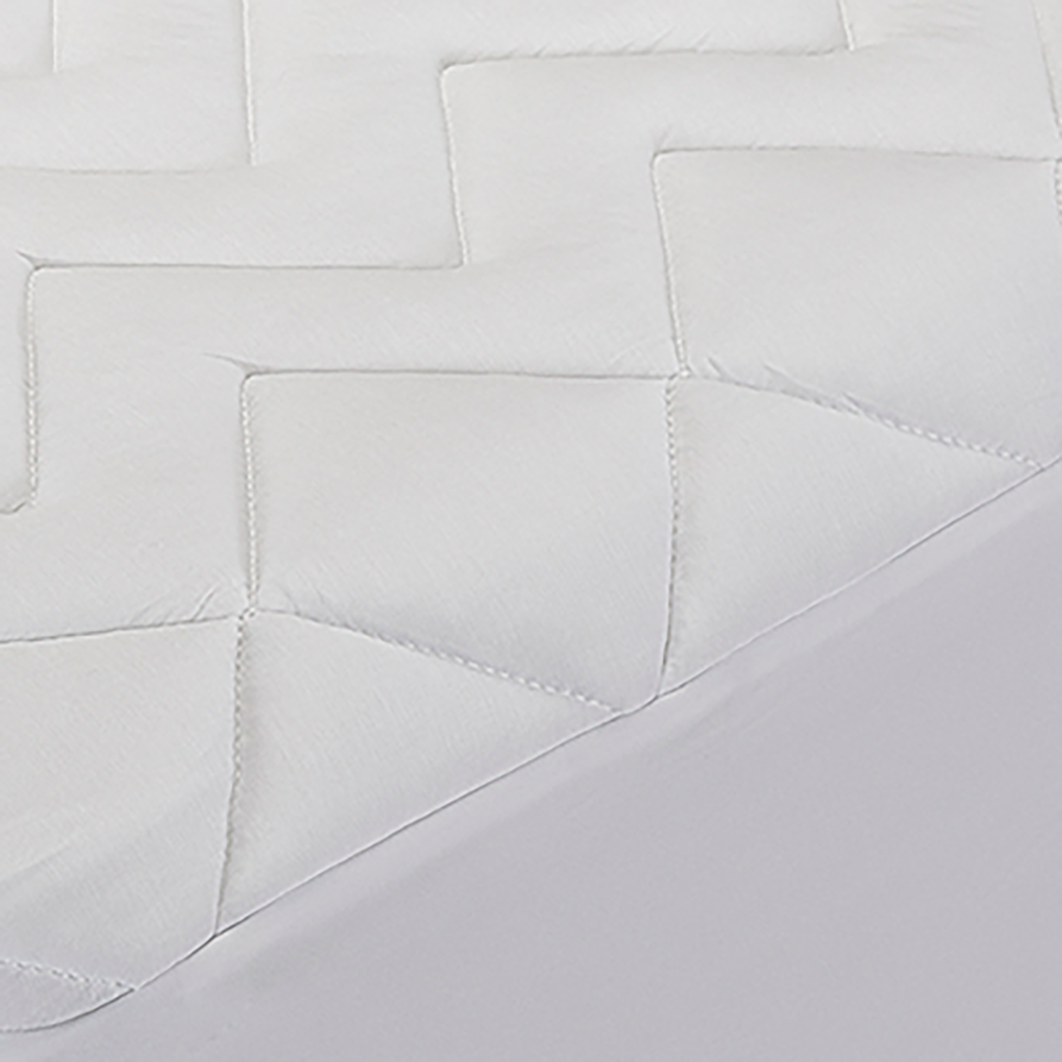 Protector de colchón acolchado blanco sobre una cama blanca, mostrando la textura y el diseño.