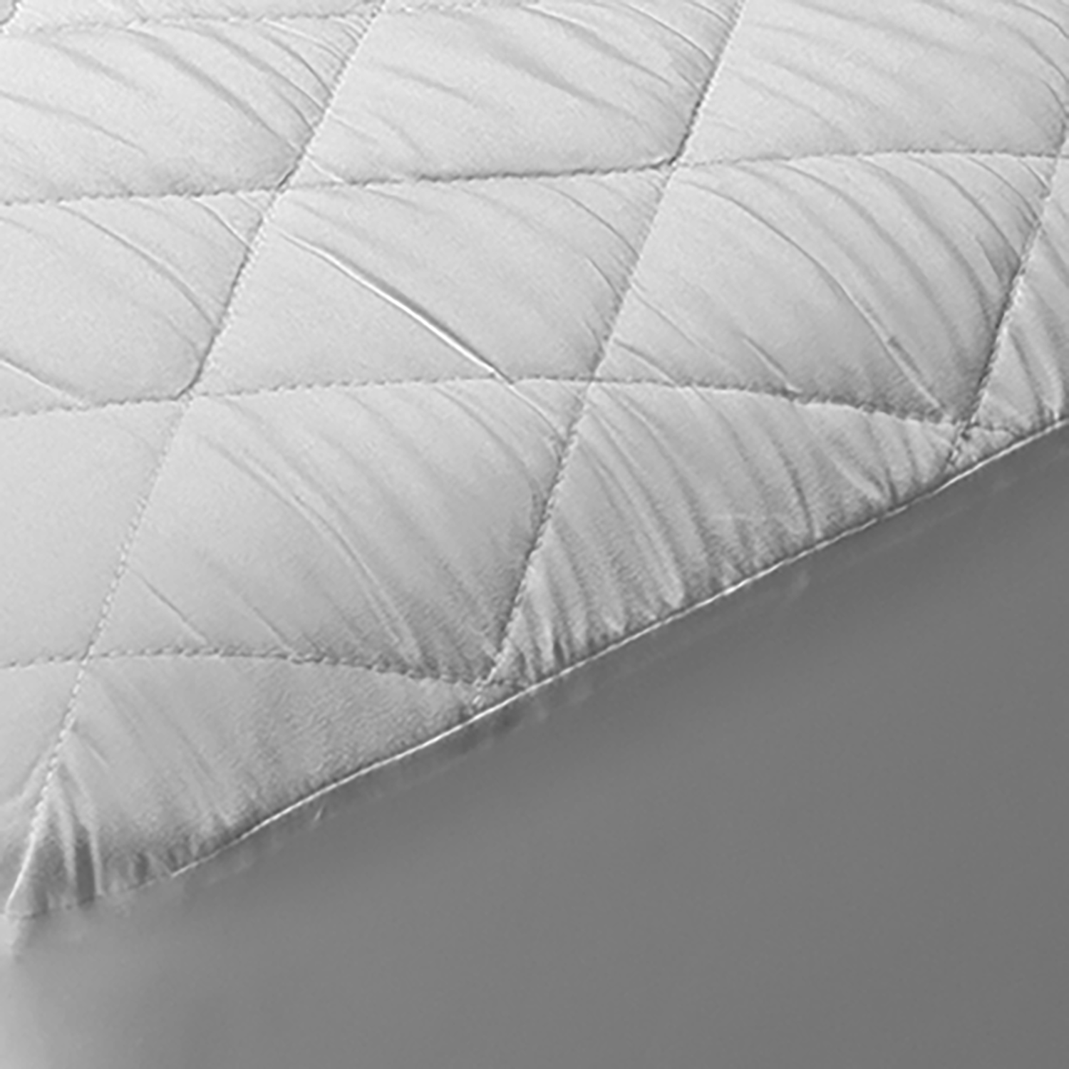 Primer plano de una funda de colchón acolchada blanca, que muestra un patrón de diamantes.
