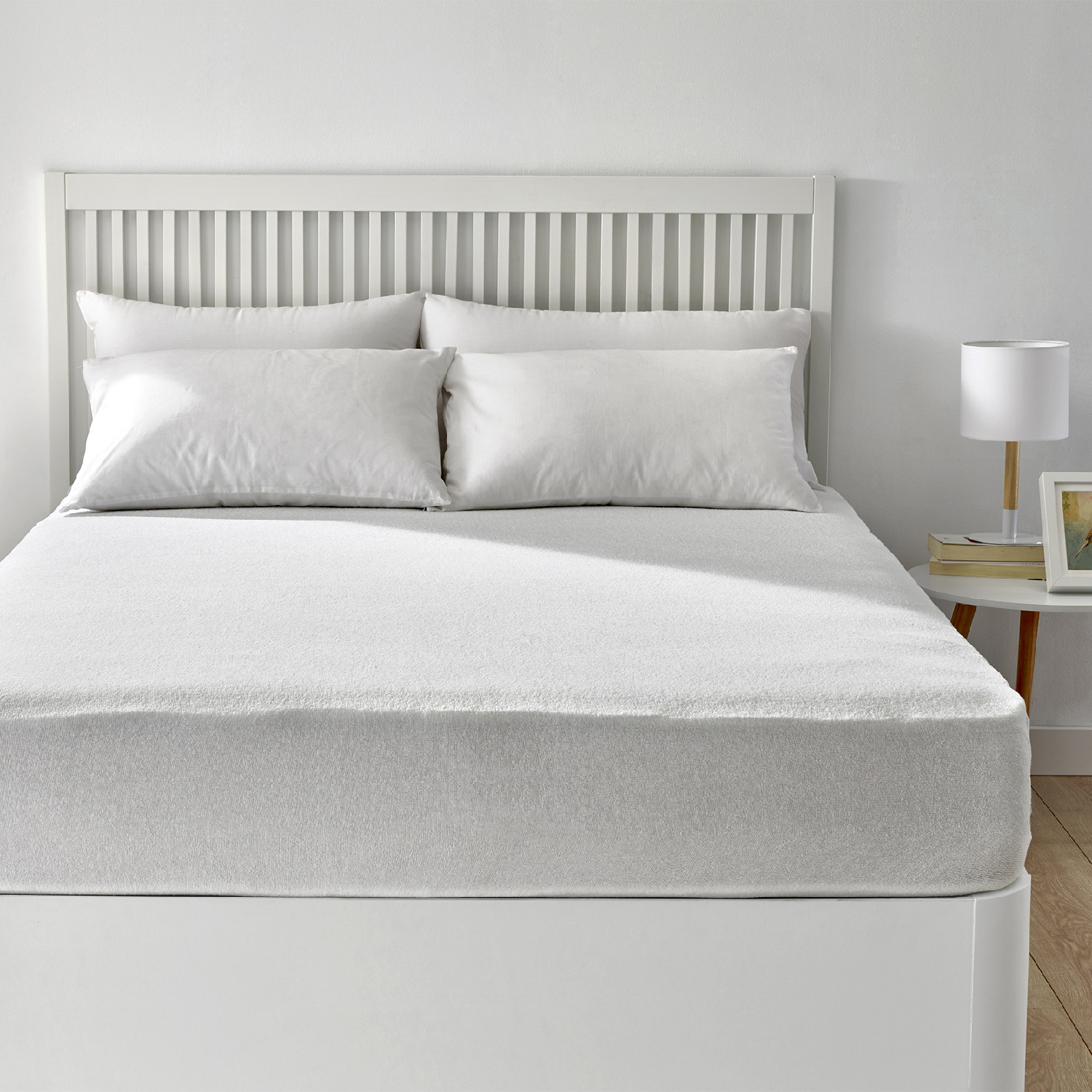 Cama blanca con dos almohadas. La cama tiene un cabecero blanco y una sábana blanca.