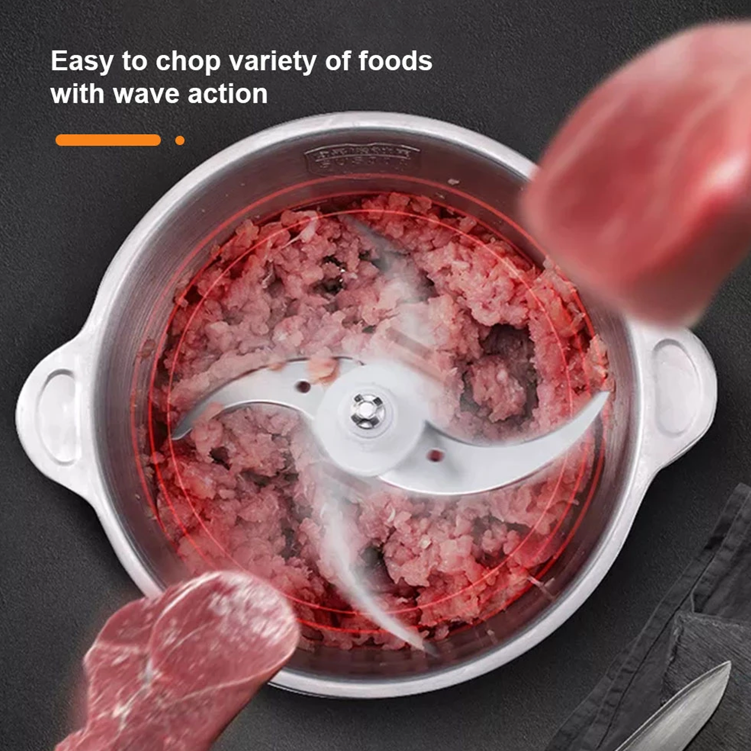 Un procesador de alimentos de acero inoxidable con carne adentro y cuchillas. Fondo rojo y blanco.