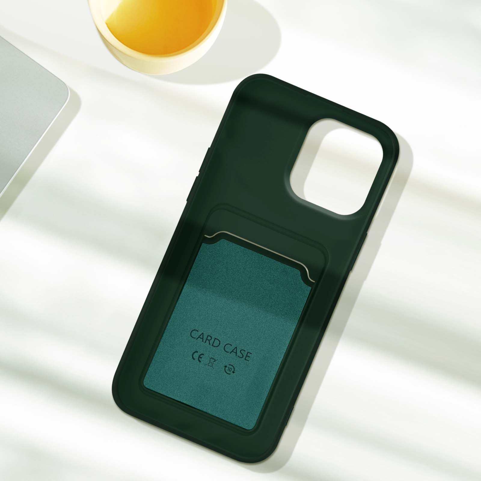 Custodia per telefono verde con fessura per carte sul retro. Una tazza e un laptop sono parzialmente visibili.