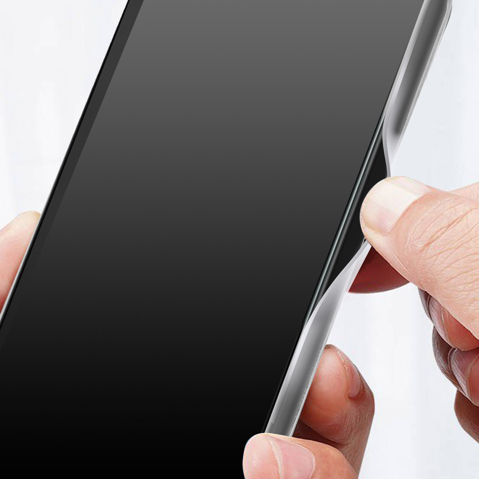 Eine Hand zieht eine Displayschutzfolie von einem schwarzen Telefon ab.