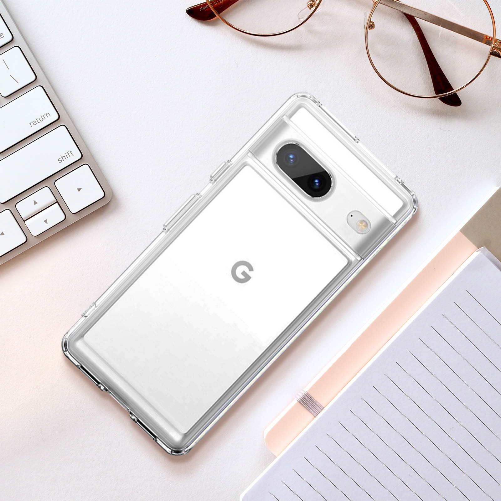 Custodia trasparente per telefono su una scrivania bianca, con un telefono all'interno e tastiera/quaderno nelle vicinanze.