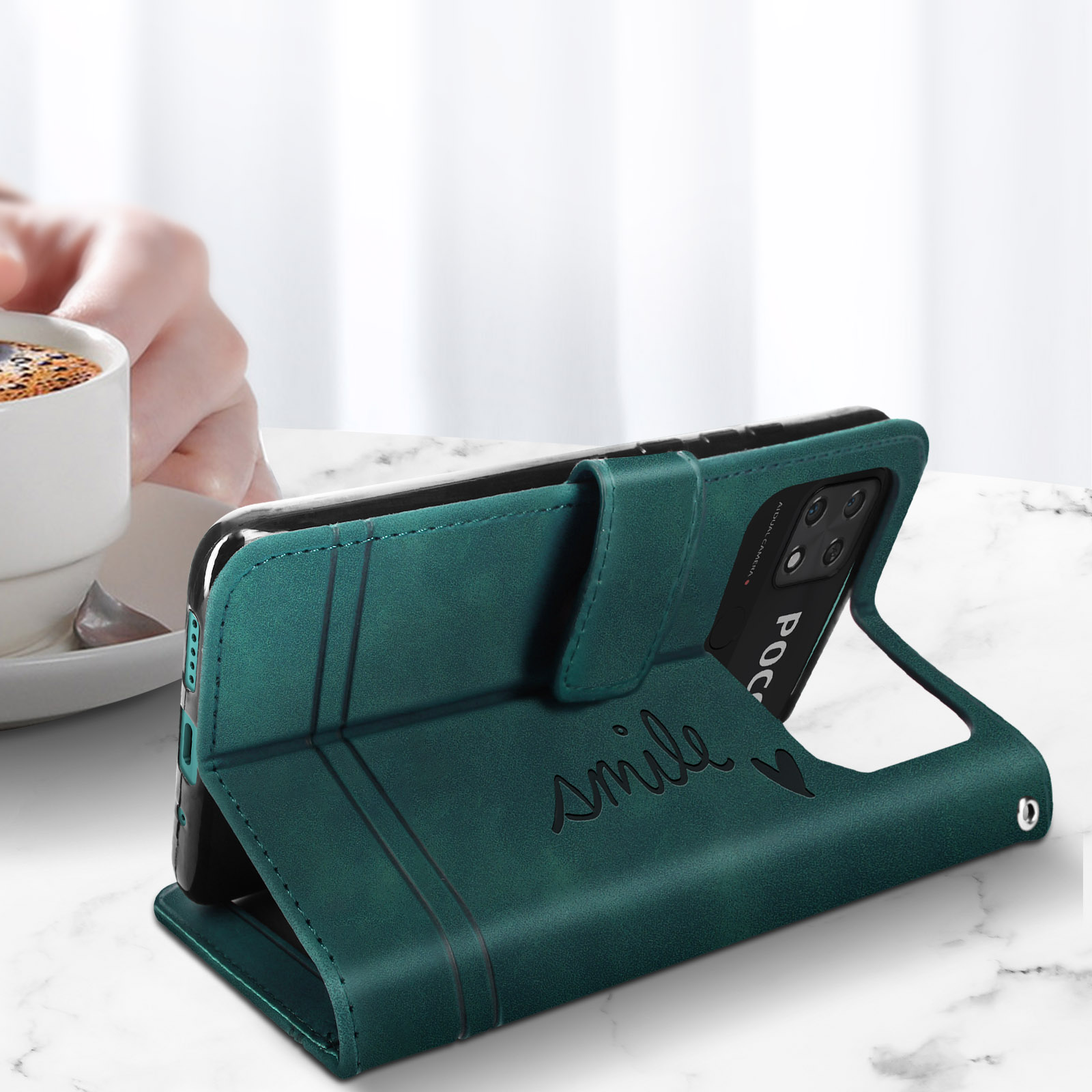 Custodia verde per telefono su tavolo di marmo, con tazza di caffè sullo sfondo.