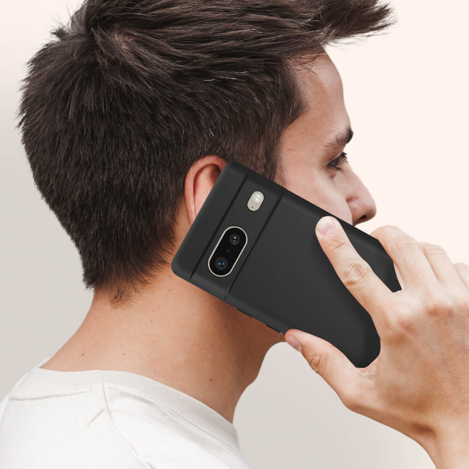 Una persona che tiene un telefono nero all'orecchio, mostrando la fotocamera e il design del telefono.