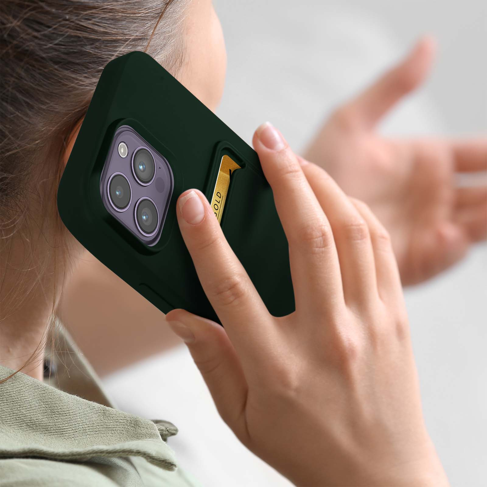 Una donna che tiene in mano un telefono con una custodia verde, parla al telefono.