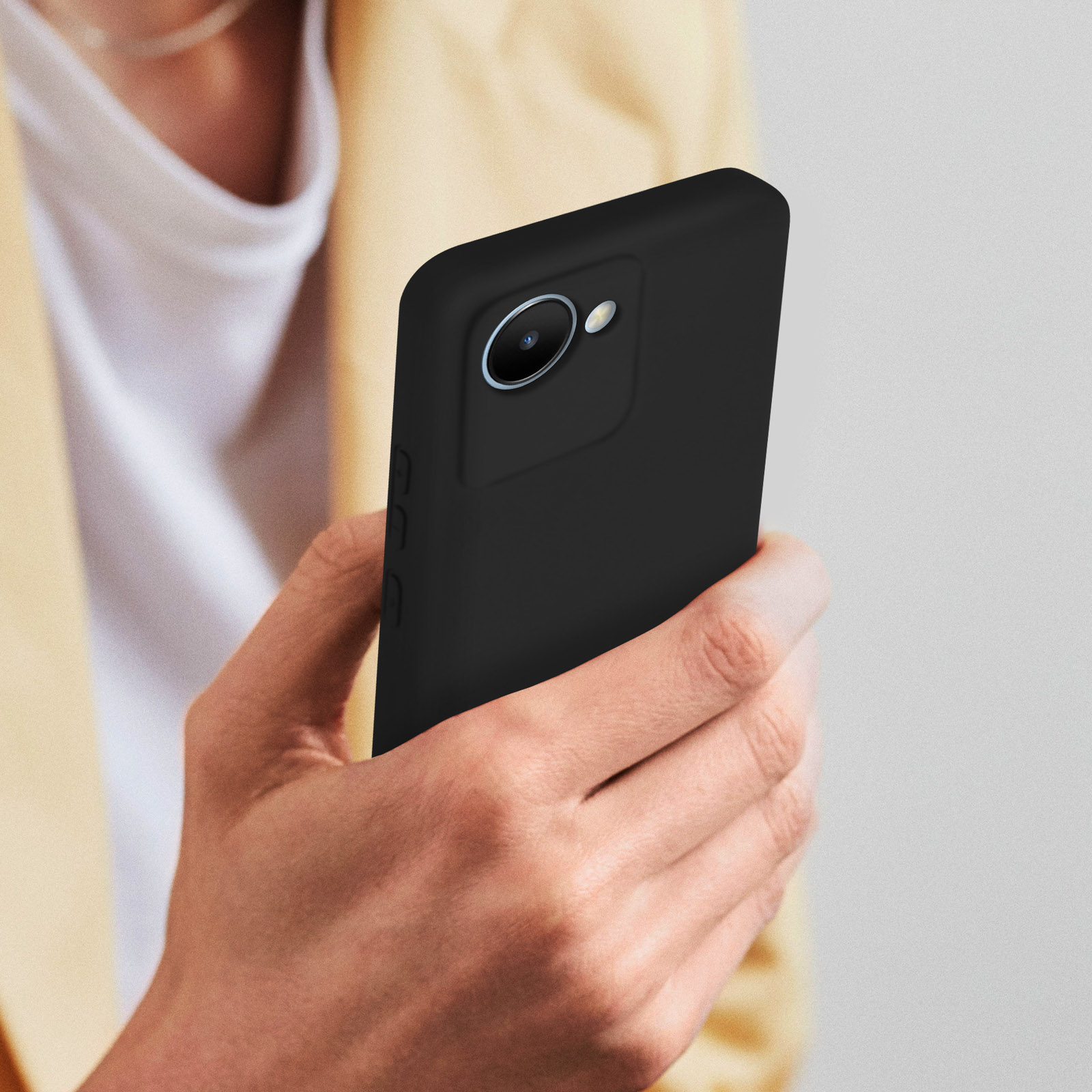 Una mano tiene un telefono nero. Il telefono ha una fotocamera ed è in una custodia nera.