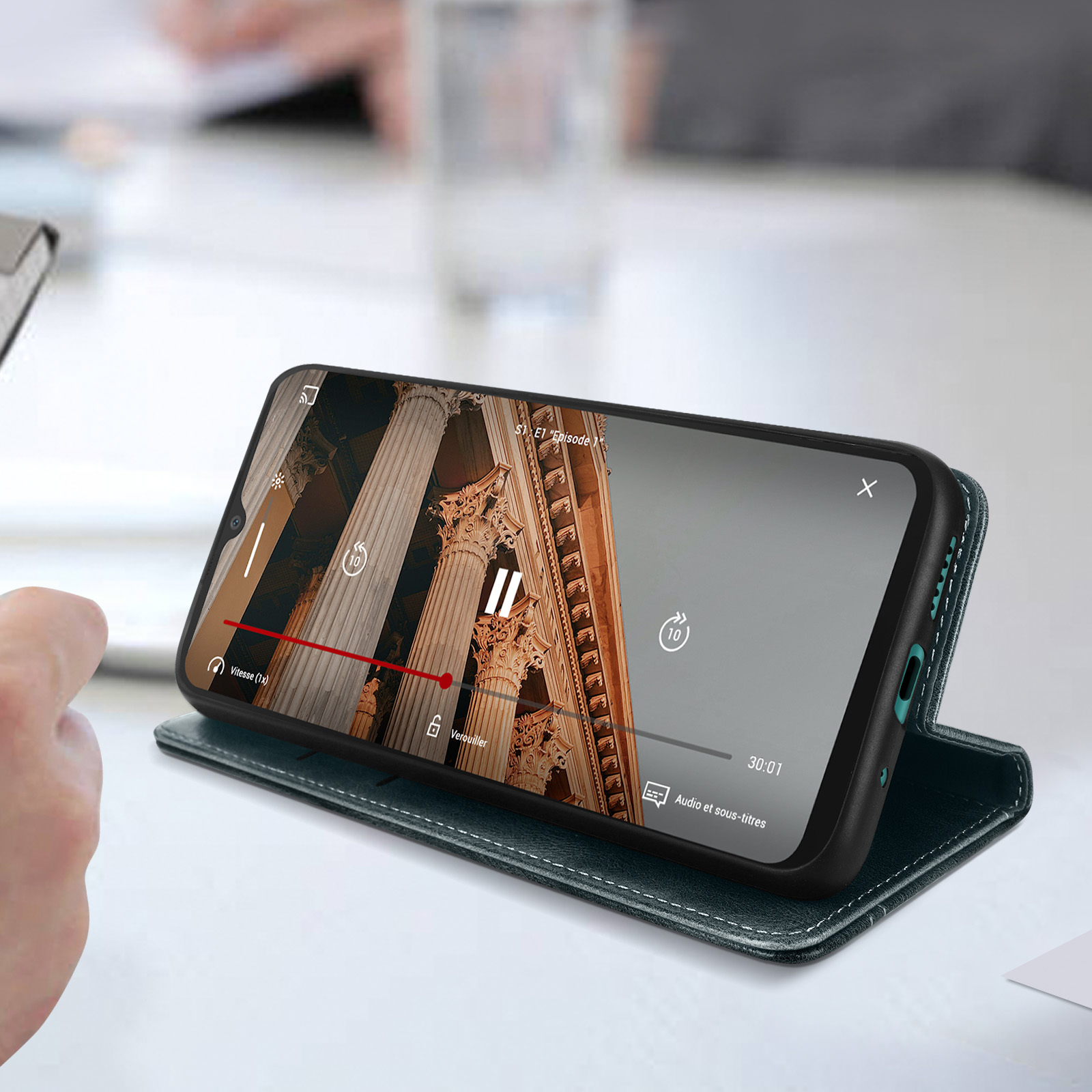 Un telefono che mostra un video su una custodia verde, con un tavolo bianco sullo sfondo.