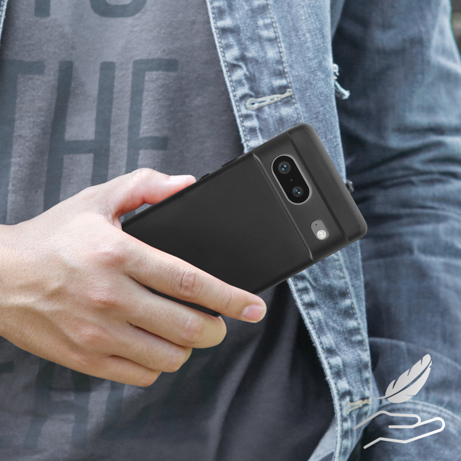 Une personne tenant un téléphone noir dans une coque noire, avec une veste en jean.