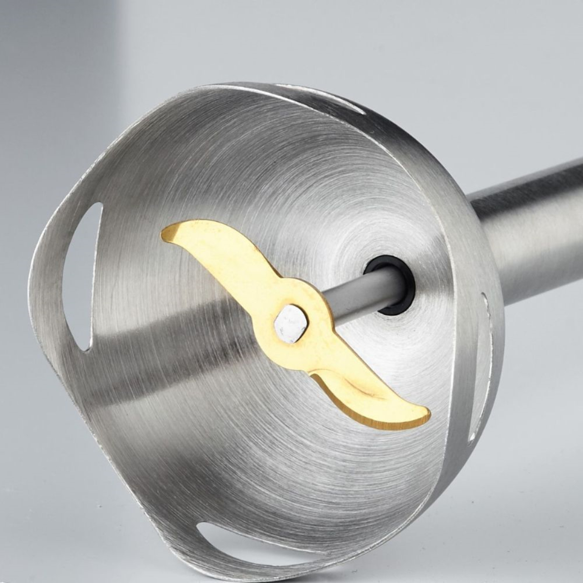 Zbliżenie ostrza ze stali nierdzewnej blendera ręcznego ze złotym ostrzem.