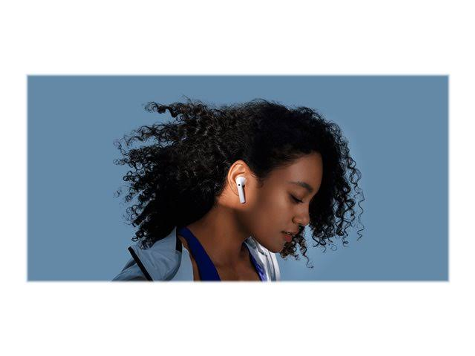 Kobieta w białych słuchawkach, ujęcie z profilu. Ma kręcone, ciemne włosy i jest na niebieskim tle.