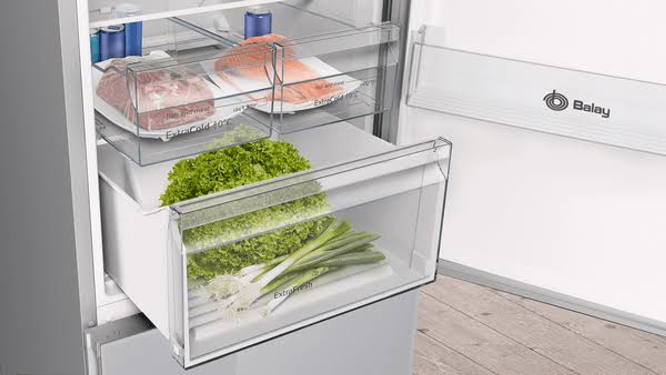 Interior de nevera con verduras y carne en cajones transparentes. Contiene lechuga, cebolletas y carne.