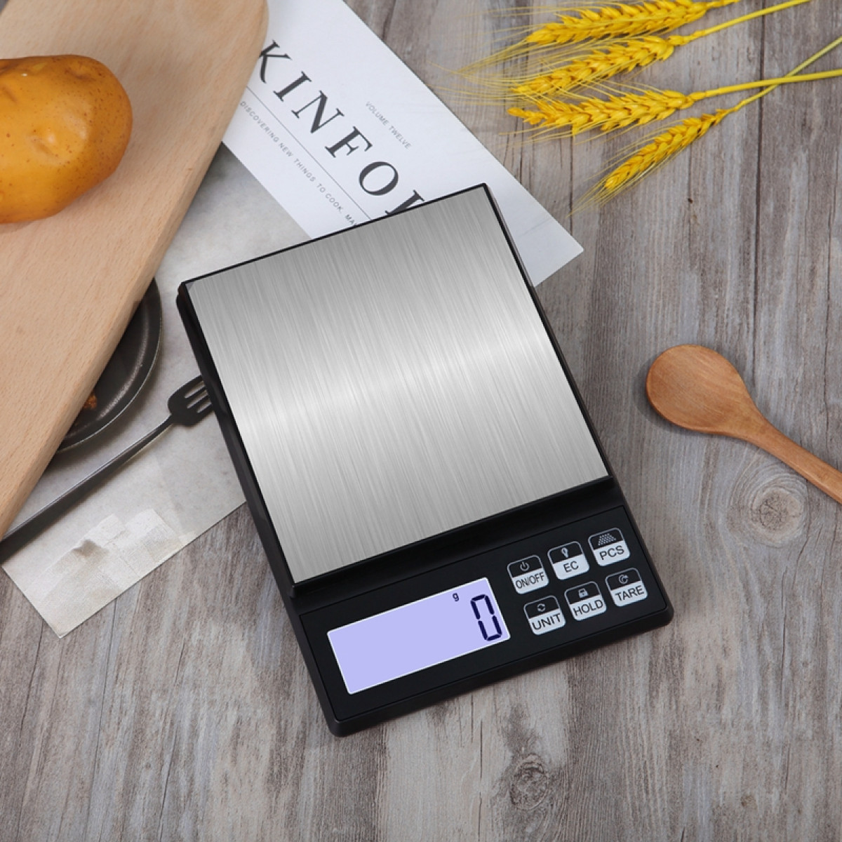 Cyfrowa waga kuchenna z białym wyświetlaczem i drewnianą łyżką obok.