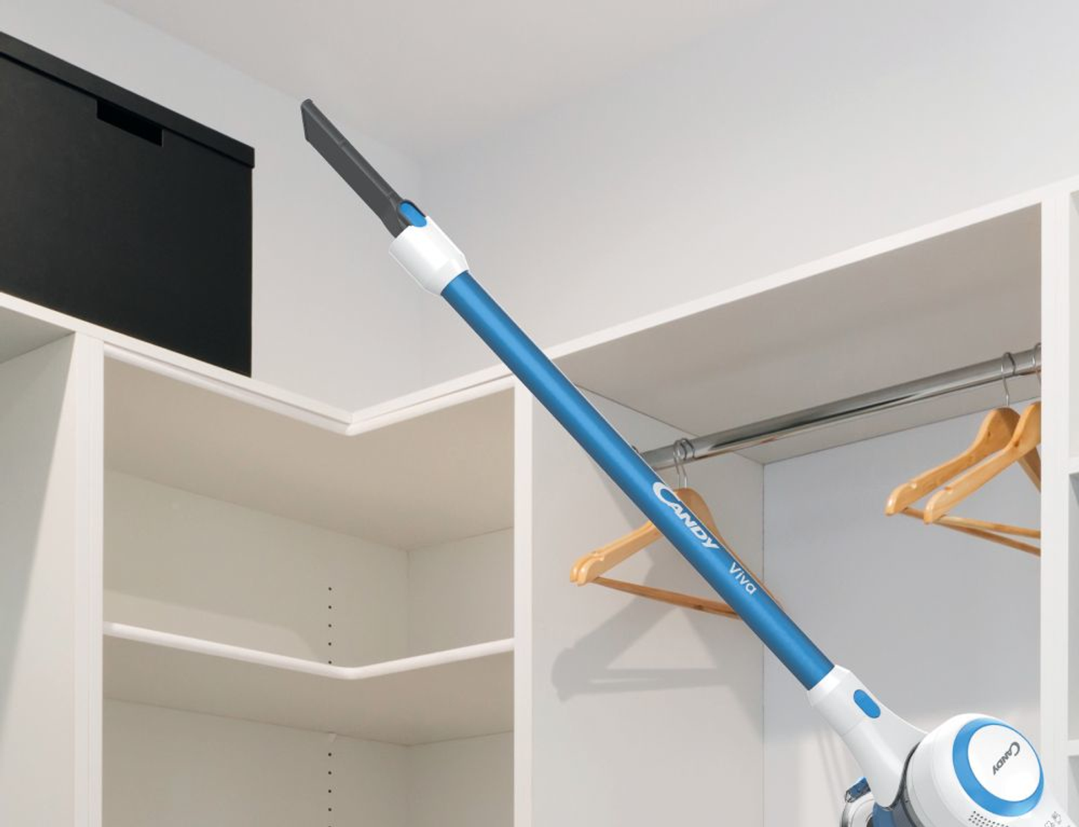 Blau-weißer Staubsauger reinigt in einem weißen Schrank. Kleiderbügel und Regale sind sichtbar.