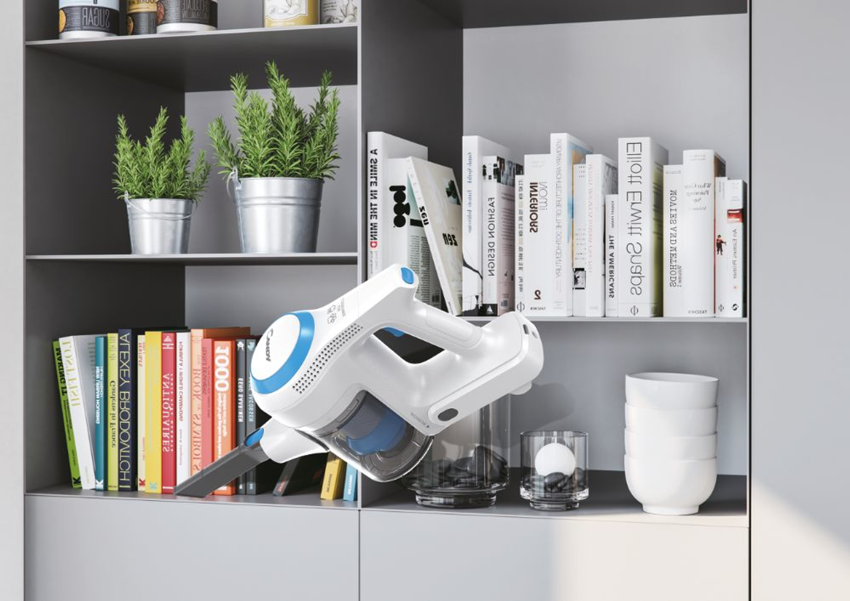 Ein weiß-blauer Staubsauger reinigt ein Regal mit Büchern, Pflanzen und Dekorationsartikeln.