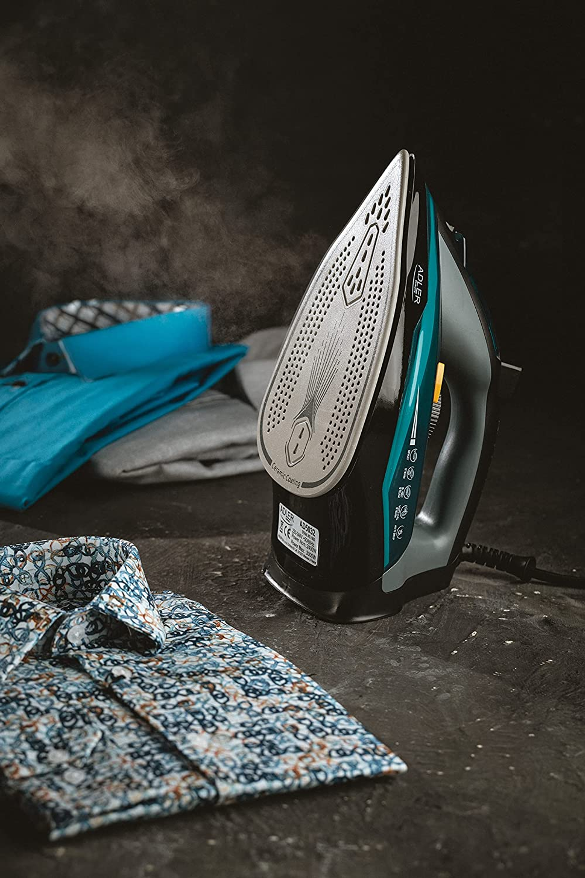 Para unosi się z czarnego i niebiesko-zielonego żelazka. Koszula jest po lewej, a inne ubrania z tyłu.