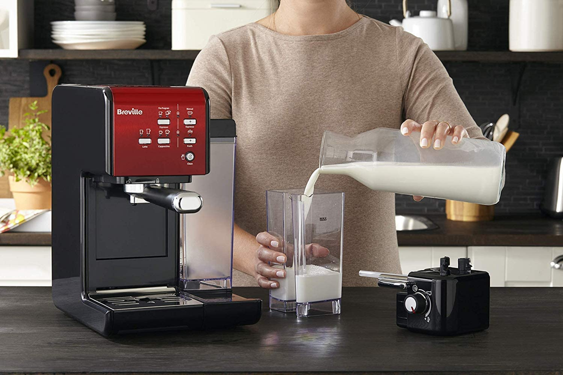 Person gießt Milch in den Milchbehälter einer Breville Espressomaschine.