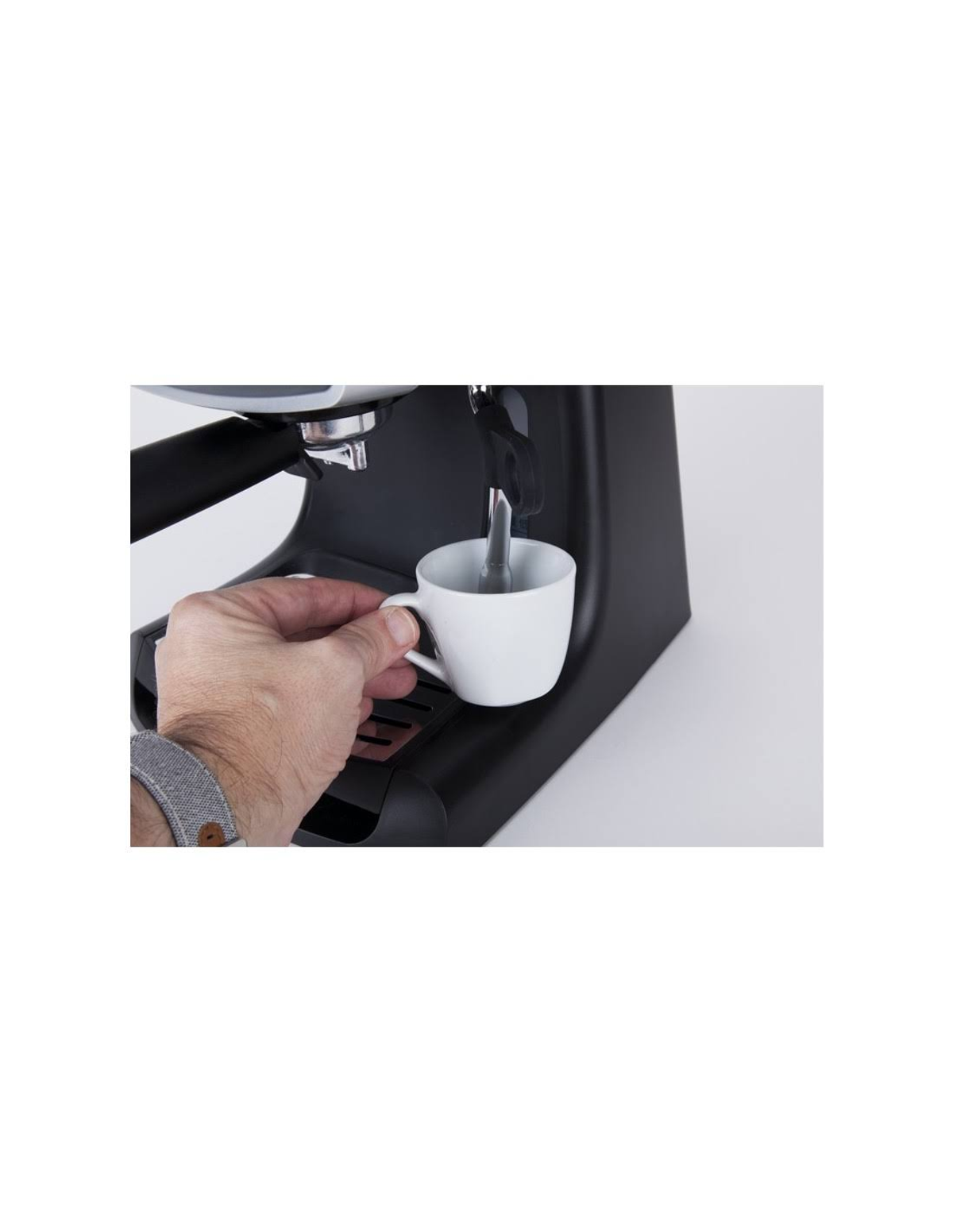 Una persona sostiene una taza blanca debajo del surtidor de una máquina de espresso negra. La máquina está sobre blanco.