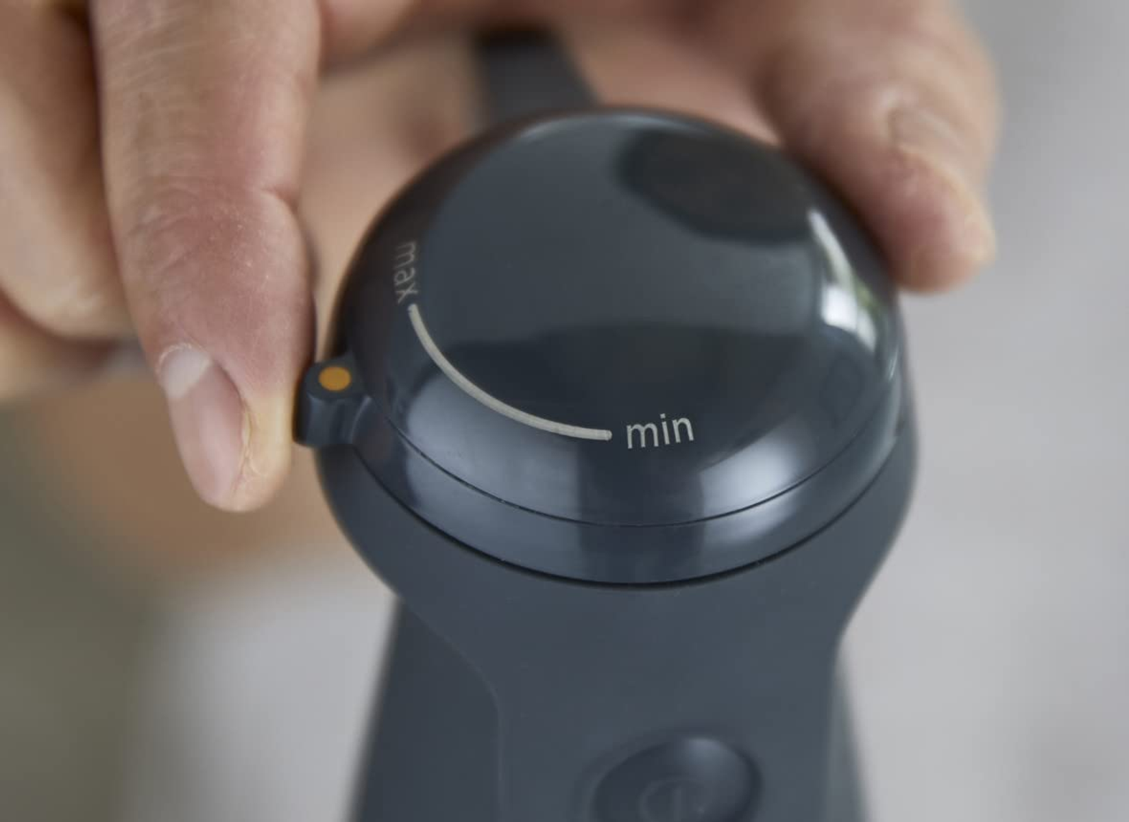 Zbliżenie pokrętła regulacji blendera ręcznego. Pokrętło jest ciemnoszare z oznaczeniami min/max.
